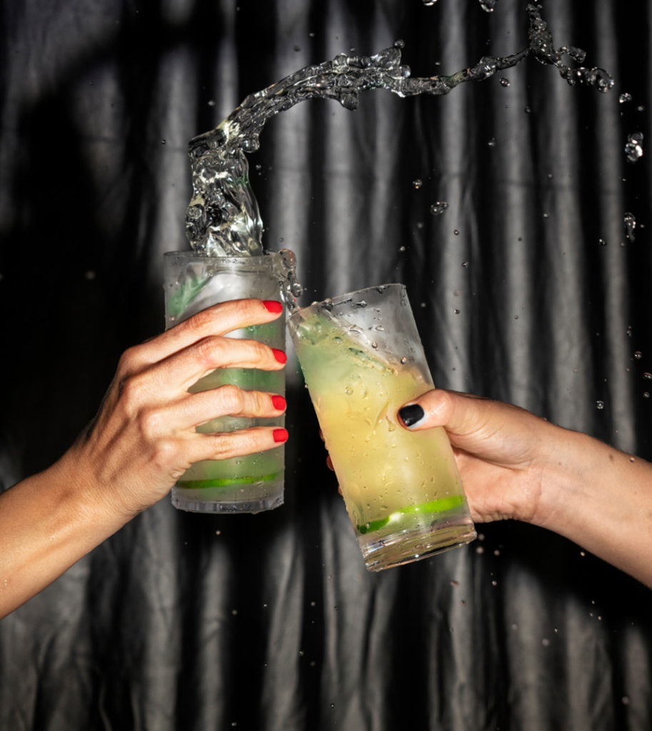 Imagen que muestra dos personas brindando con vasos de tubo rellenos de bebida.