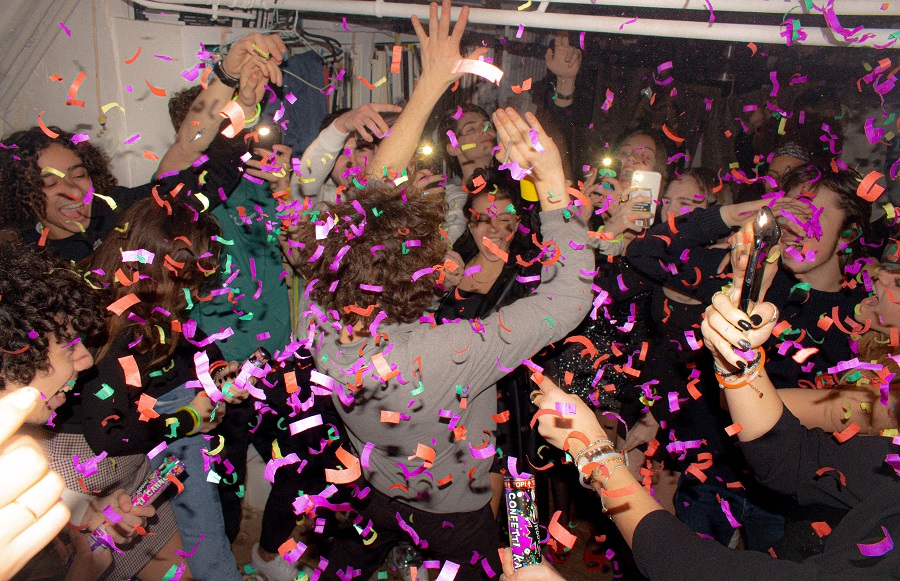 Imagen que muestra un grupo de gente disfrutando de una fiesta, bailando y grabando con sus teléfonos móviles, en lo que podría ser una discoteca sostenible.